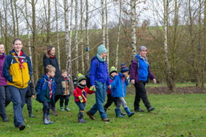 A group of Squirrels and adult volunteers walking through the campsite..