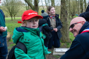 A Squirrel wearing a red Squirrel hat, next to a smiling volunteer.